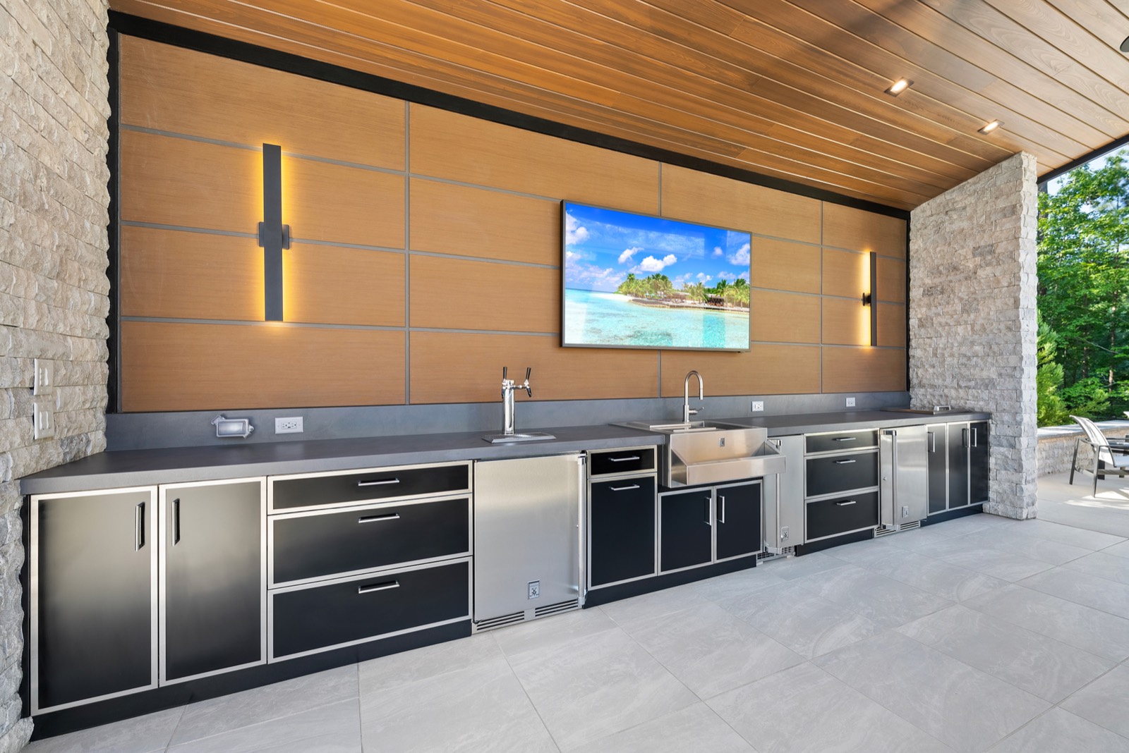 Covered outdoor kitchen with black cabinets and wood wall panels